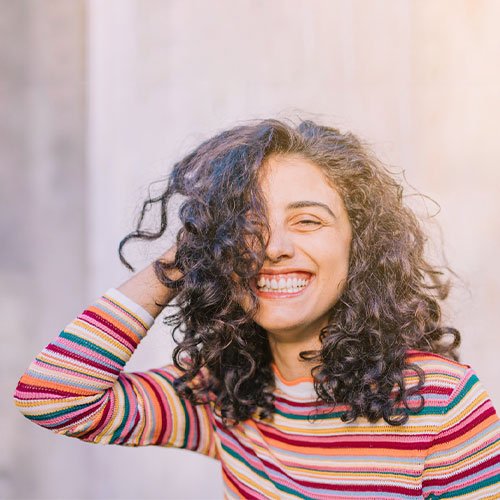 Foto de perfil idealizadora X - Segurando o cabelo e sorrindo